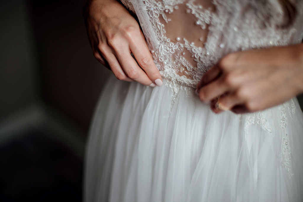 Detail shot of bride adjusting Hanrie Lues wedding dress with delicate beadwork
